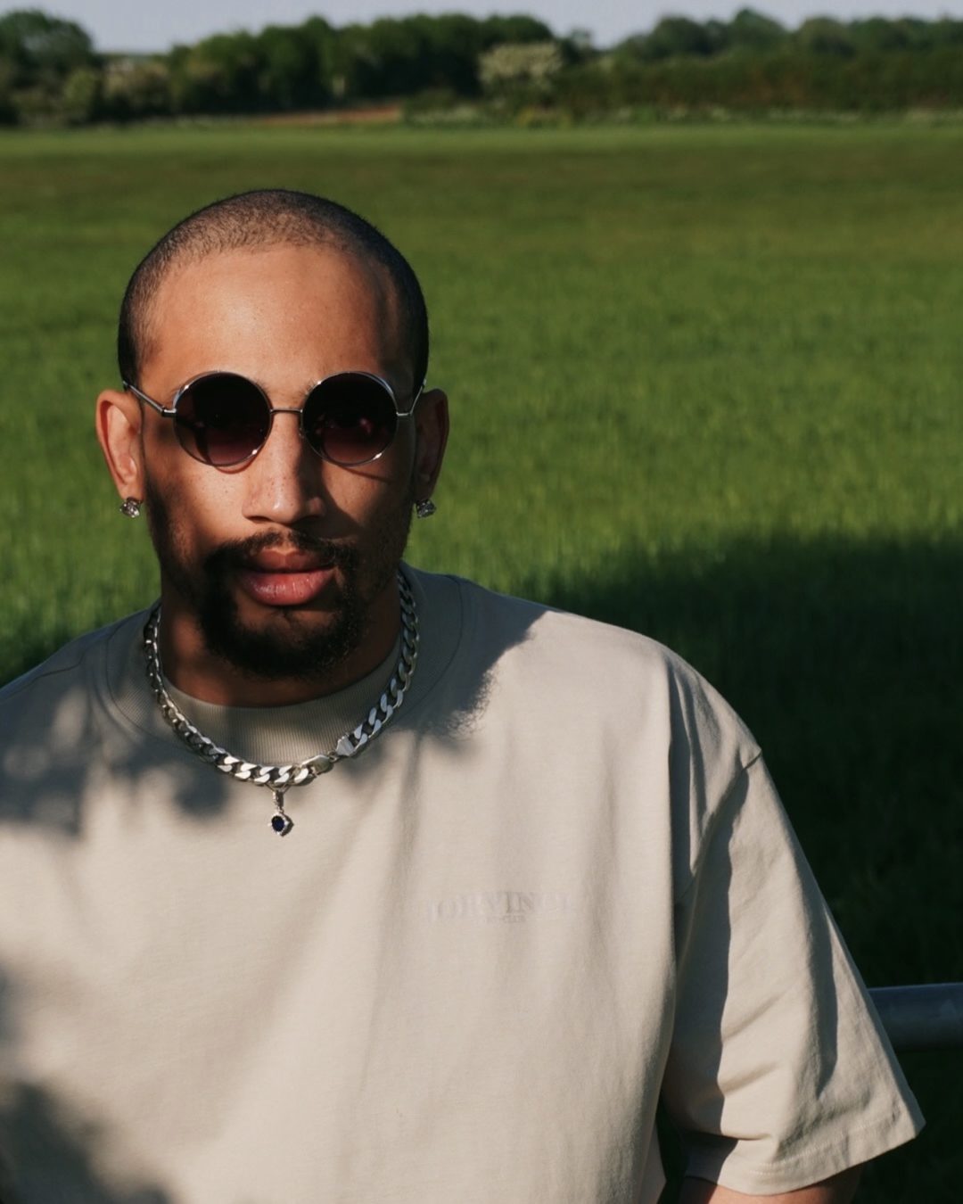 Aaron Fife summer portrait in round sunglasses in a green field